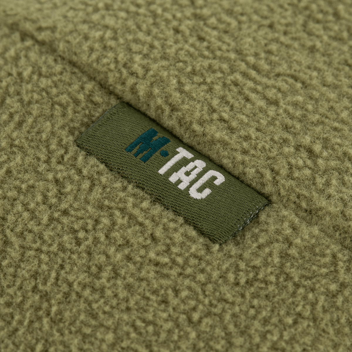 Nærbillede af M-Tac Watch Cap Elite Fleece Beanie Hat Slimtex med logo på armygrøn fleece-materiale.