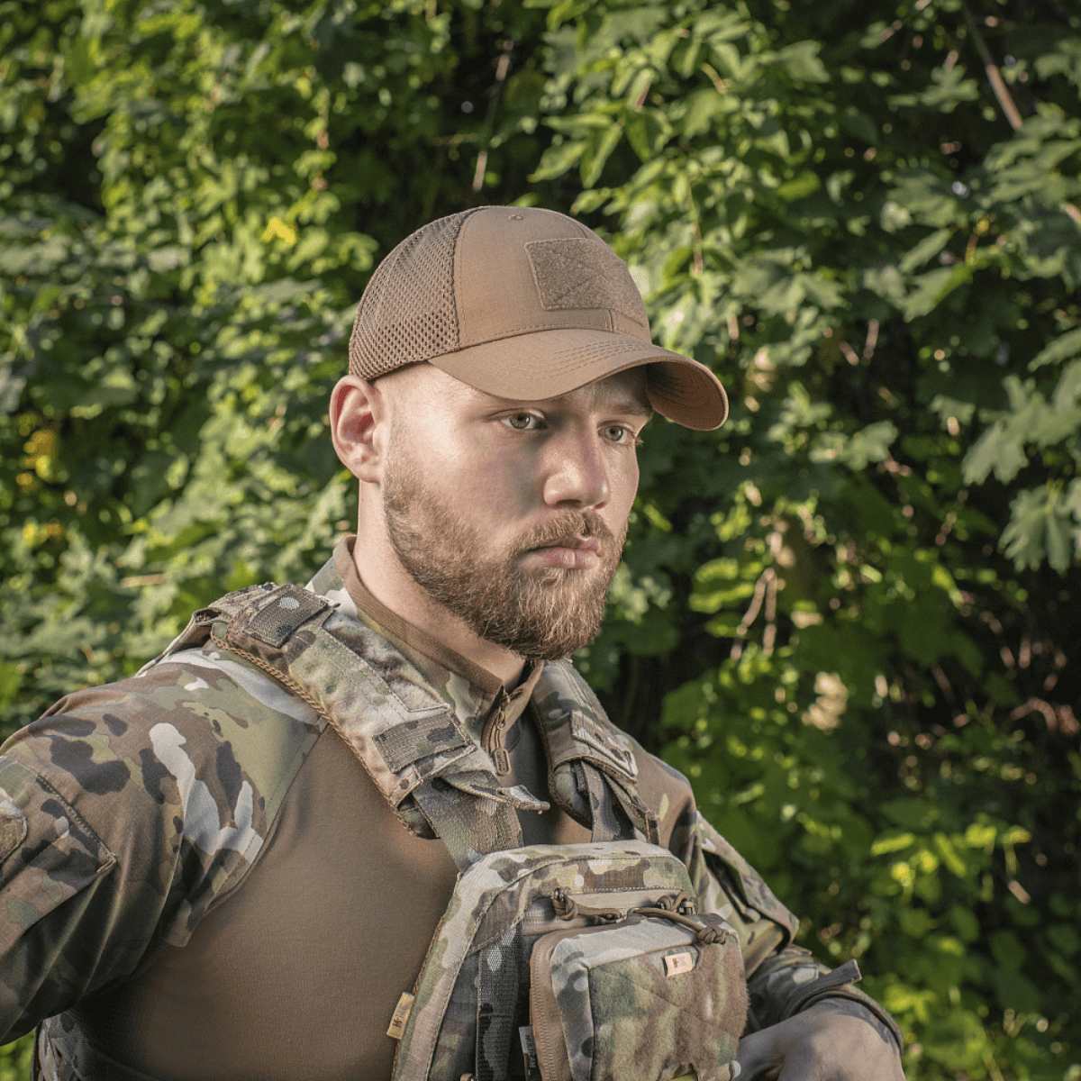 Mand i skov bærer M-Tac Baseball Cap Ripstop Elite Flex og camouflageudstyr