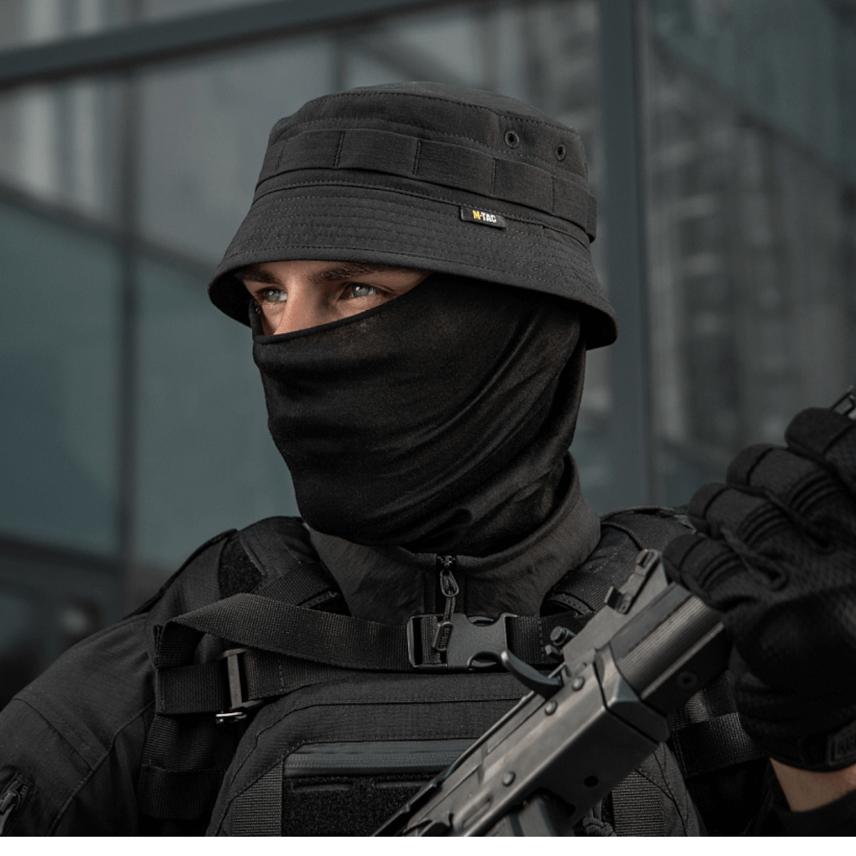 M-Tac Panamahat Gen. II Summer Flex i sort, bæres af en mand i taktisk udstyr, ideel til solbeskyttelse og komfort i varme omgivelser.