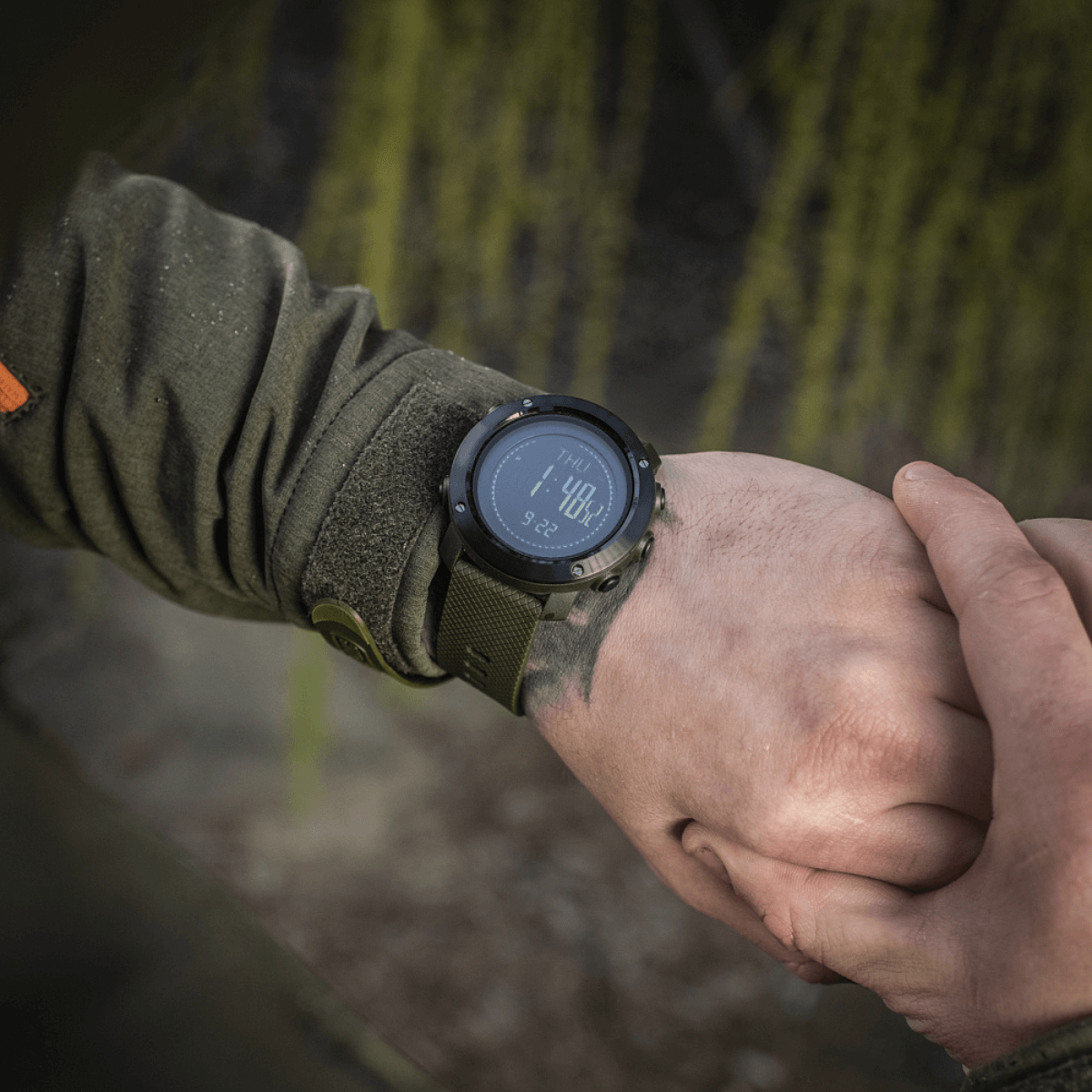 Person wearing M‑Tac Multifunktionelt Taktisk Ur displaying digital time, ideal for outdoor and military use.