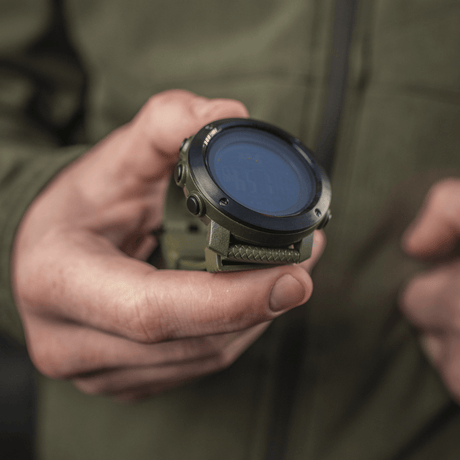 M‑Tac Multifunktionellt Taktiskt ur hålls i handen, idealiskt för friluftsliv och militärt bruk, visar robust design och avancerade funktioner