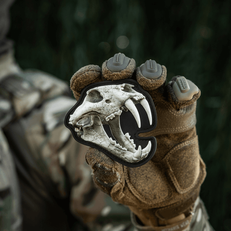 M‑Tac Patch Old Tiger med 3D-tigerkranium, hålls av soldat i kamouflagekläder, symboliserar mod och erfarenhet, PVC med velcrofäste.