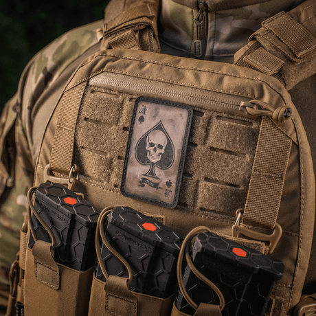 Taktisk väst med M-Tac Patch Ace of Spades, dödskalle‑design, Cordura 500D, Velcro-montering, vintagelook, visar stridsanda och attityd.