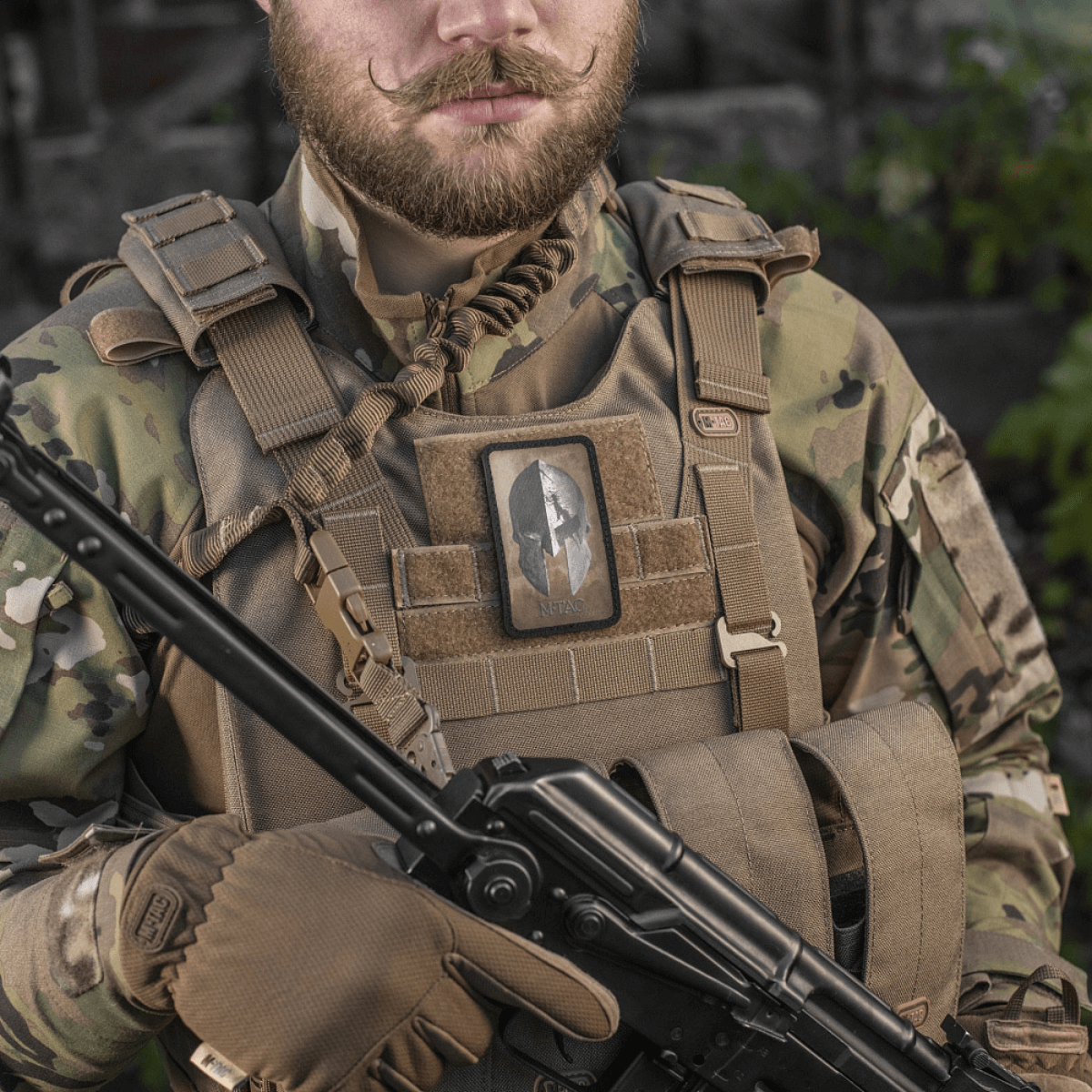 M-Tac Spartan Hjelm Patch i brug på taktisk vest, symboliserer mod og styrke, vintage Spartan design, velcro fastgørelse til udstyr.