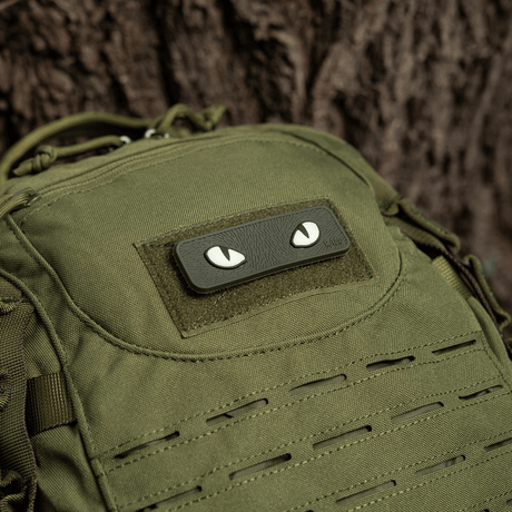 M-Tac Cat Eyes 3D PVC-patch på grön ryggsäck bredvid ett träd.