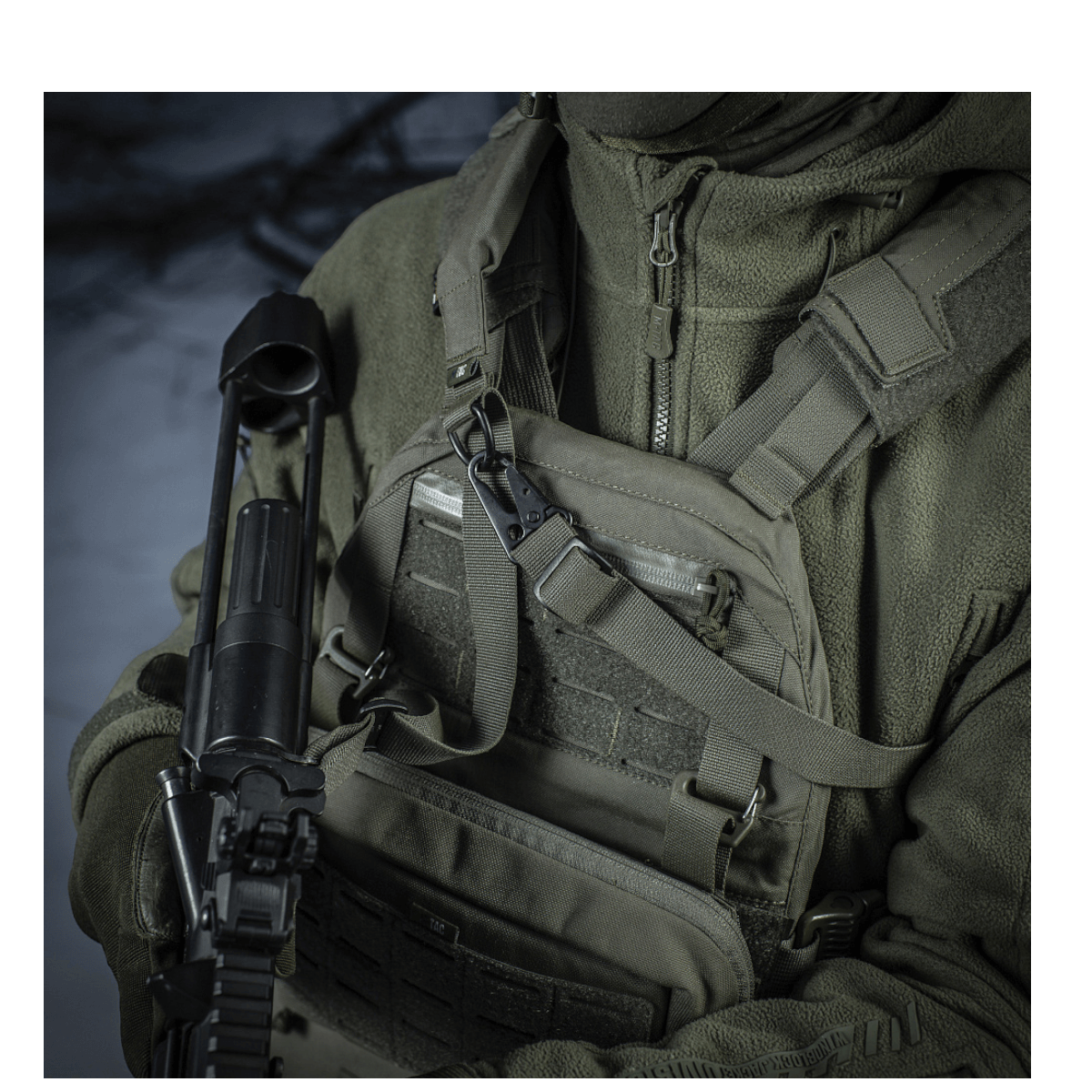 Soldat iført taktisk udstyr bærer et gevær med M-Tac Universal Våbenrem i et skovmiljø for optimal komfort og funktionalitet.