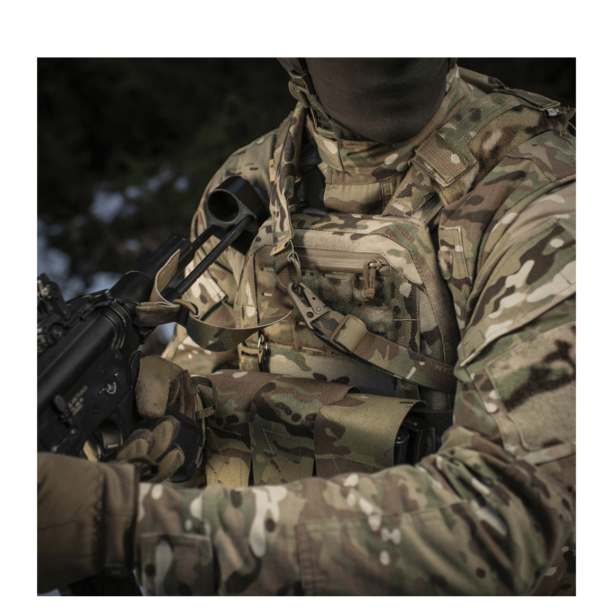 Militærperson iført camouflage udstyr med M-Tac Universal Våbenrem og gevær i hænderne, klar til handling.