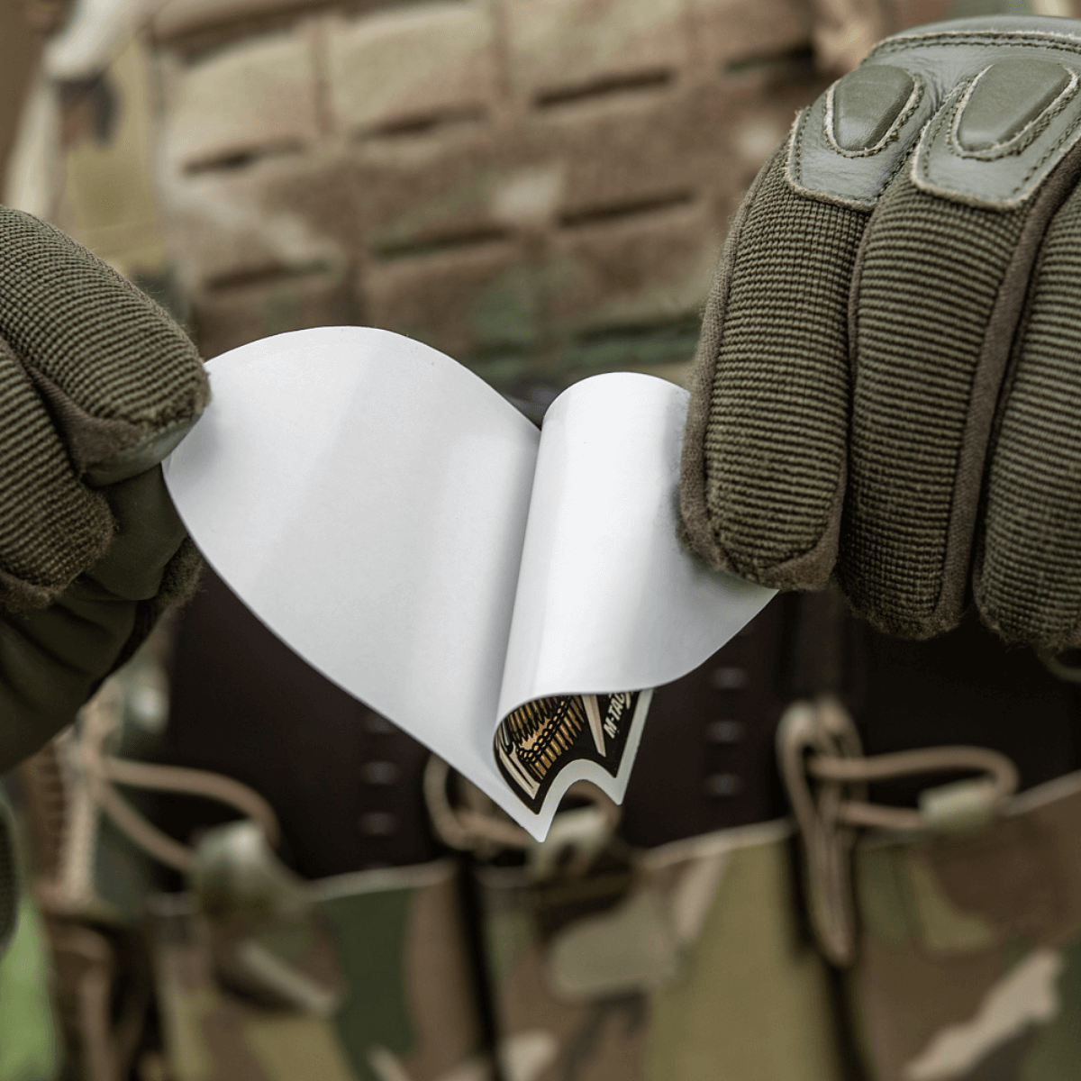 M-Tac Sticker Valkyrie holdt af person i camouflage, klar til brug. Viser den beslutsomme krigsgudinde med M4 gevær på Arrowhead patch.