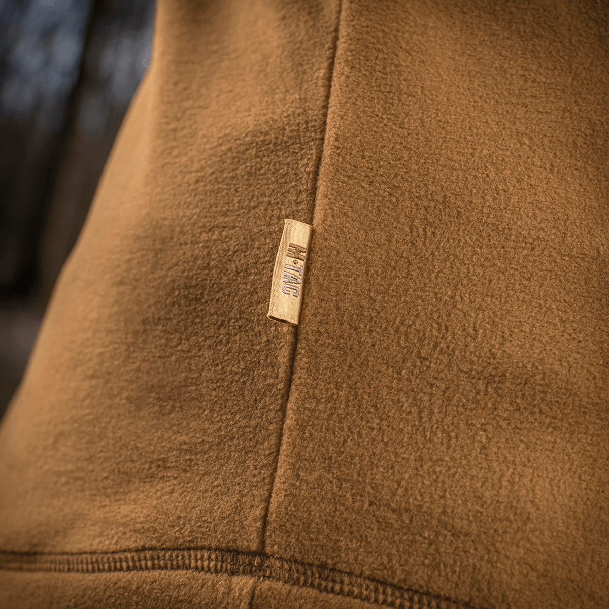 Et nærbillede af M-Tac Delta Polartec Fleecejakke med fokus på det bløde, slidstærke Polartec® Micro Series-stof og mærkeetiketten.