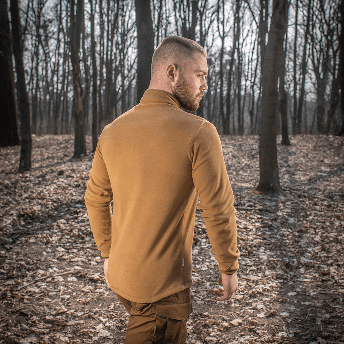 Mand iført M-Tac Delta Polartec Fleecejakke i skovomgivelser, fremstillet af slidstærk Polartec® Micro Series-fleece.