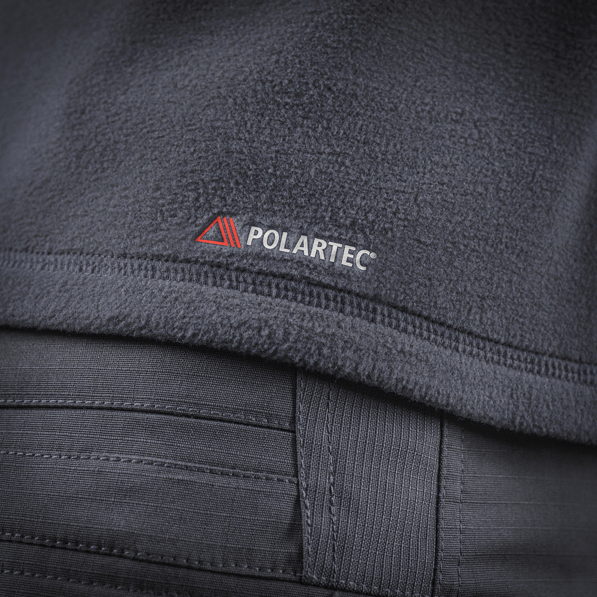 M-Tac Delta Polartec Fleecejakke stofdetalje med Polartec® logo, ideel til kolde dage med varmeisolerende egenskaber og let design.