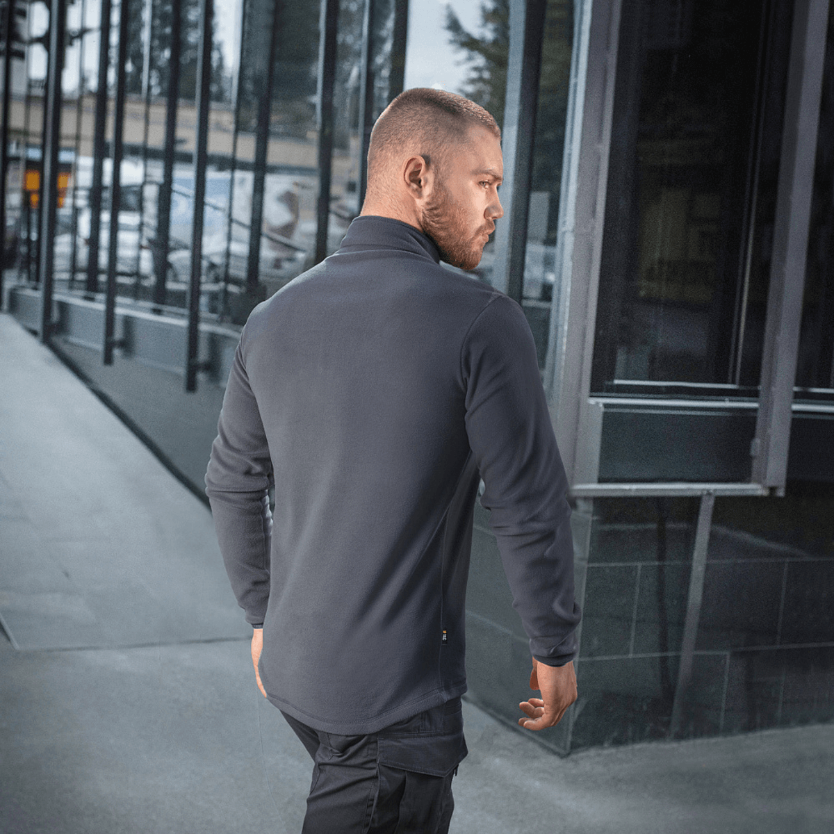 M-Tac Delta Polartec Fleecejakke i grå, set bagfra på en mand i urbane omgivelser. Stilren fleecejakke med Polartec® Micro Series.