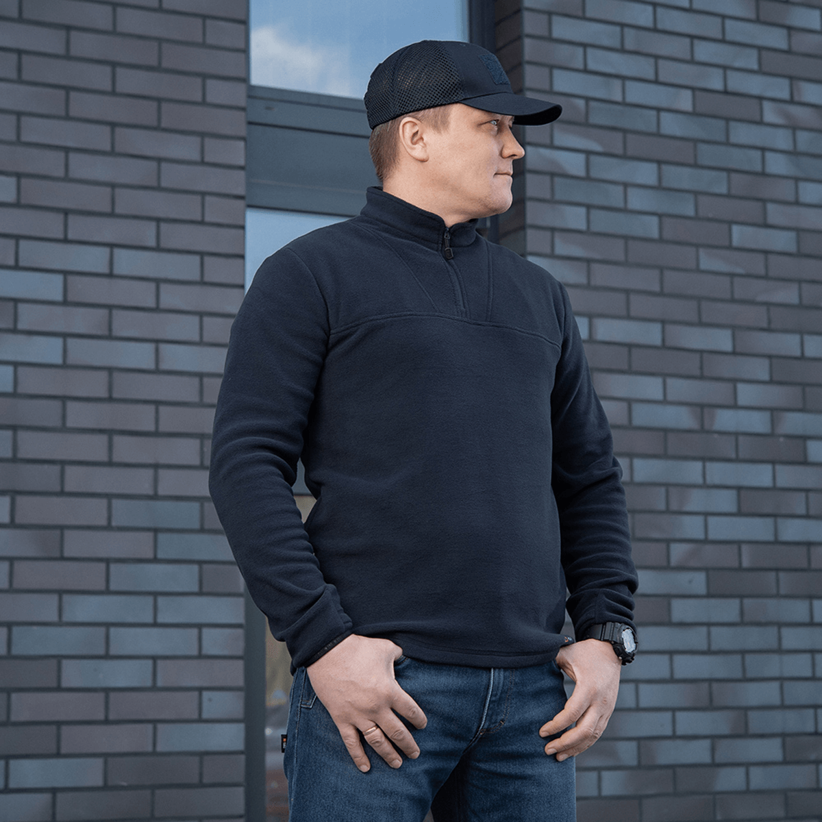 Mand iført M-Tac Delta Polartec Fleecejakke foran murstensvæg.