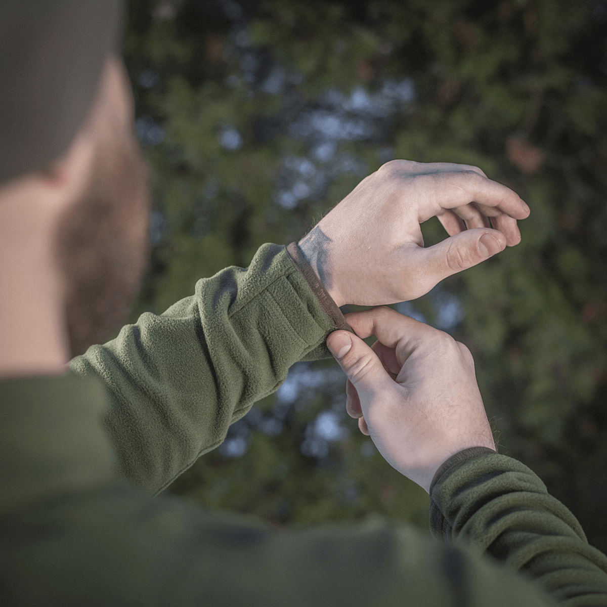 Person iført M-Tac Delta Polartec Fleecejakke justerer ærmet. Fokus på komfort og funktionalitet til kolde dage.