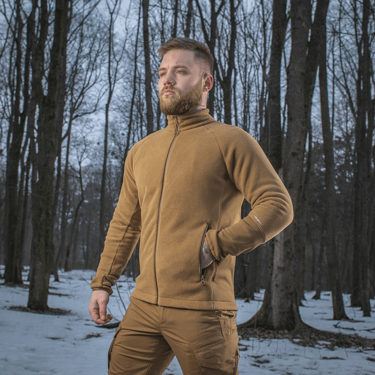 Mand iført M-Tac Polartec Sport Fleecejakke i en skov om vinteren