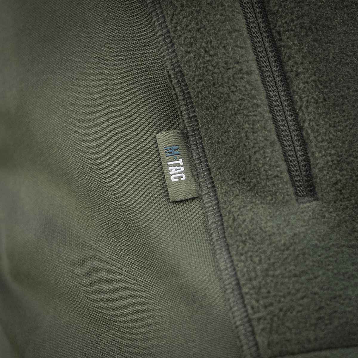 Nærbillede af M-Tac Polartec Sport Fleecejakke, viser mærket og tekstur af Polartec® 200 Series fleece i oliven farve.