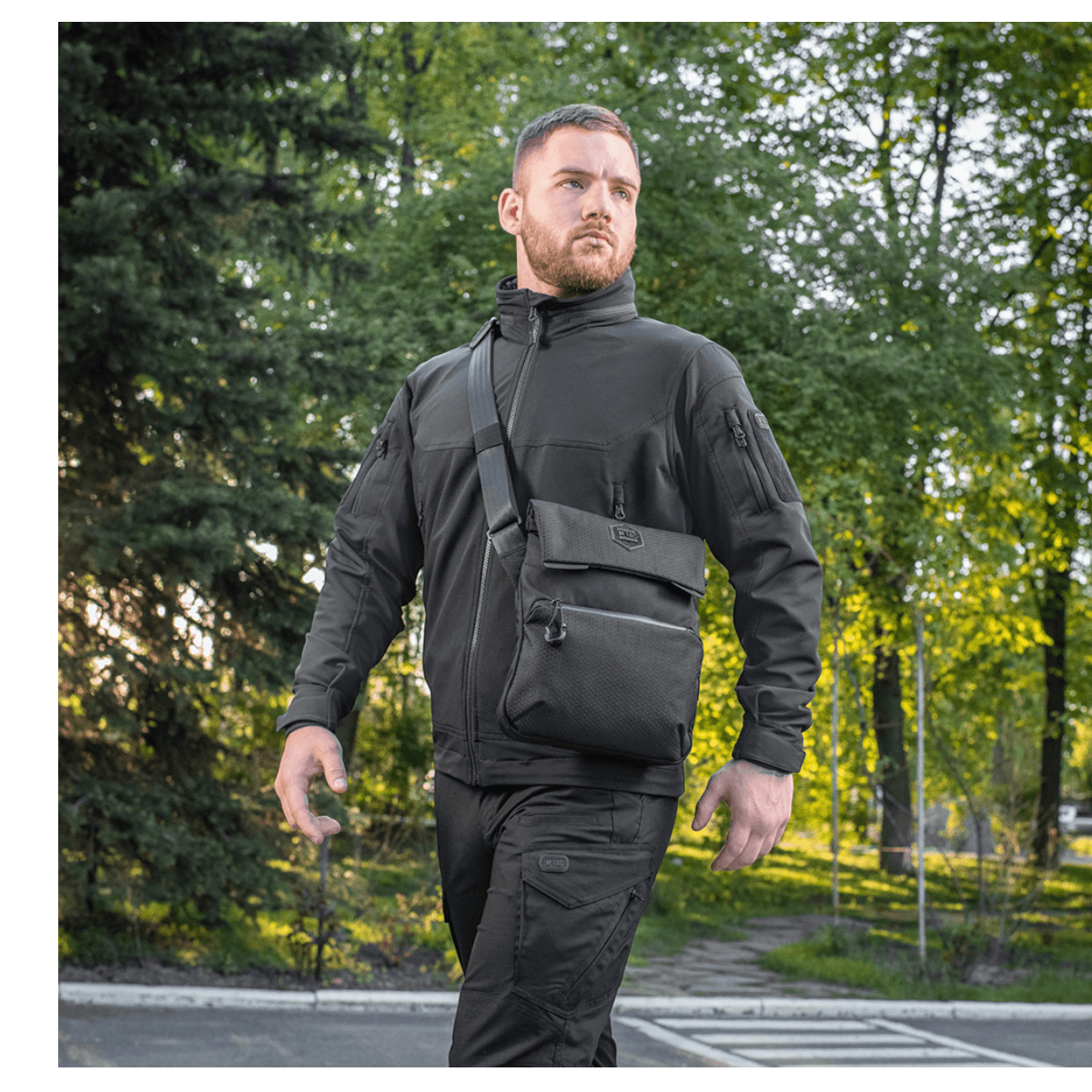 Mand bærer M-Tac Konvert Taske Elite i sort, lavet af Cordura-materiale, ideel til komfortabel og hurtig adgang udendørs.