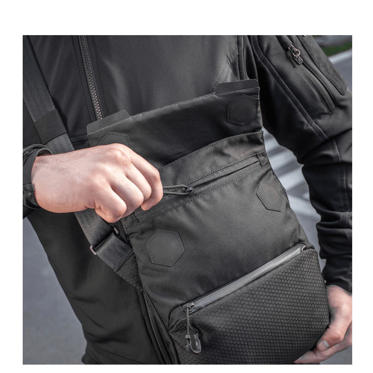 Mand med M-Tac Konvert Taske Elite, lavet af holdbar Cordura, med magnetlukning og justerbar skulderrem.