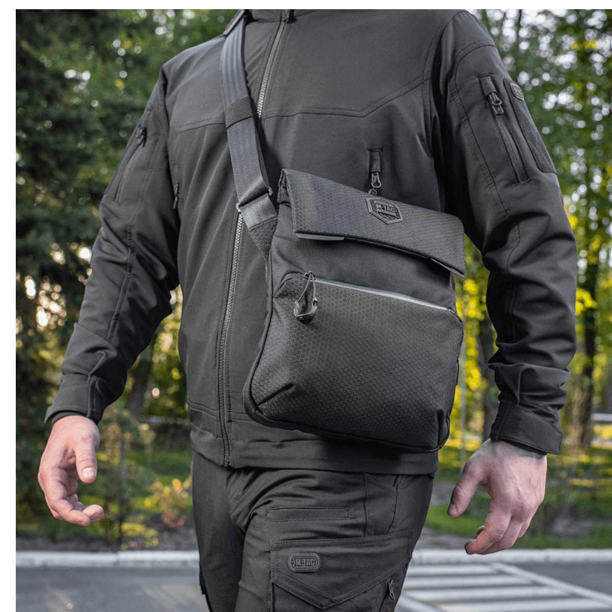 Mand bærer M-Tac Konvert Taske Elite i sort Cordura, udendørs, med justerbar skulderrem og magnetlukning, stilet urban design.
