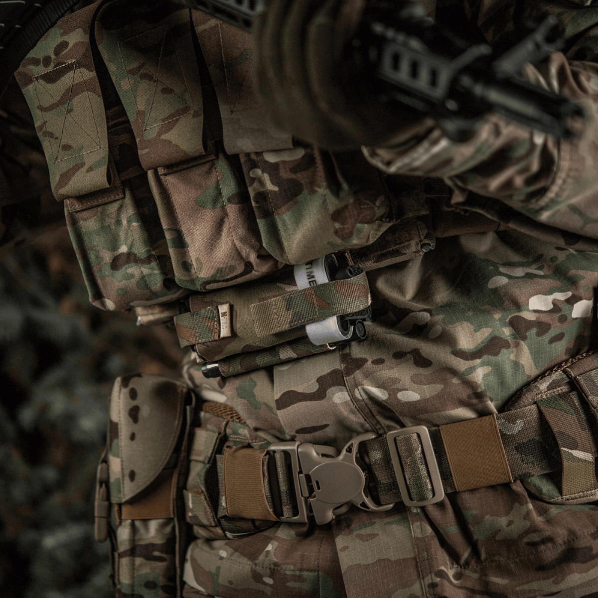 M-Tac Elastisk Tourniquet Holder Gen. III monteret på soldatens camouflagedragt, lavet af slidstærk Cordura 500D med elastik og Texcel-stropper.