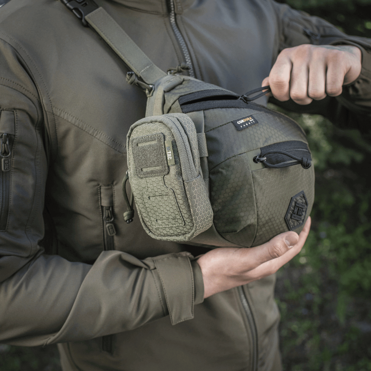 M-Tac PC Utility Taske Elite Hex monteret på en person, viser stilfuldt design og holdbare materialer, ideel til hurtig adgang til nødvendigheder.
