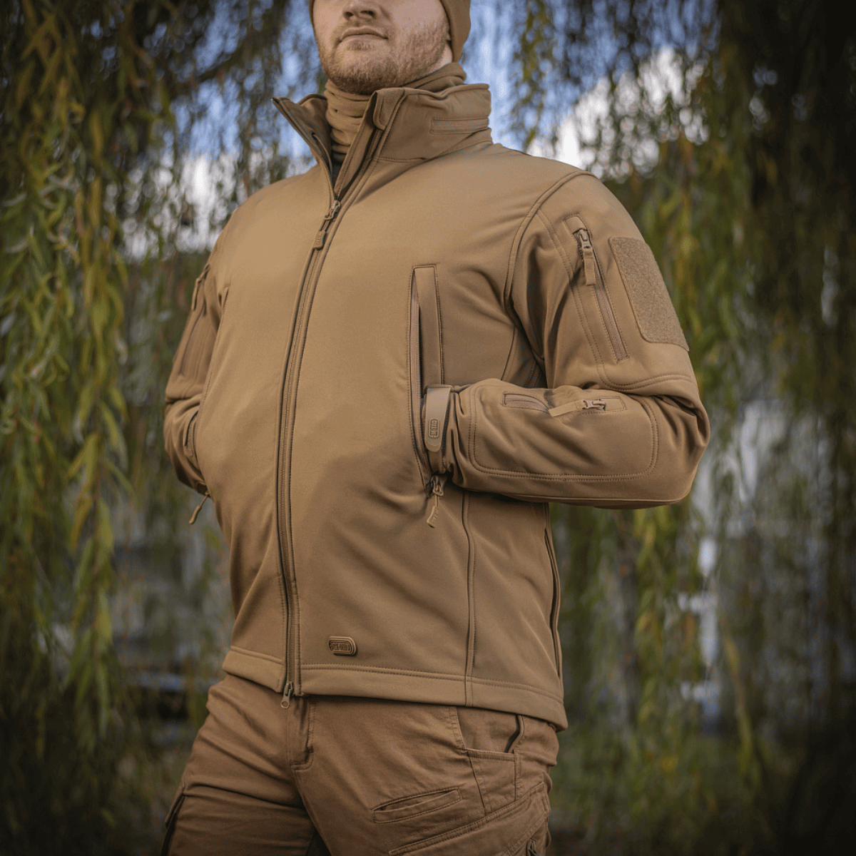 M-Tac Soft Shell Jakke i naturmiljø, viser jakke med indre polyuretan-membran og fleece-lag, ideel til beskyttelse mod vind og vejr.