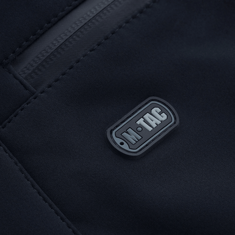 Nærbillede af M-Tac Bukser Soft Shell Vinter med detalje af logo og lynlås, ideelle til kolde vejrforhold.
