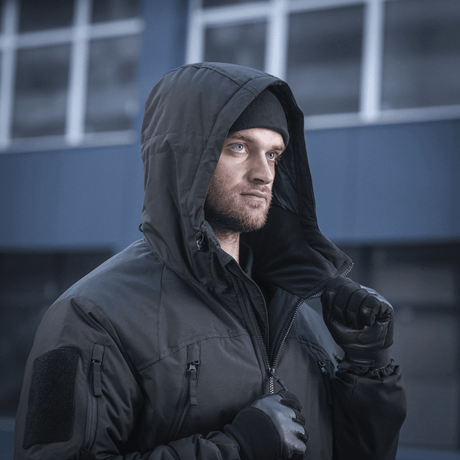Mand i M-Tac Alpha Gen.III Pro Vinterjakke, ideel til -20°C, med vandafvisende ydre og G-Loft isolering, udendørs i en urban setting.