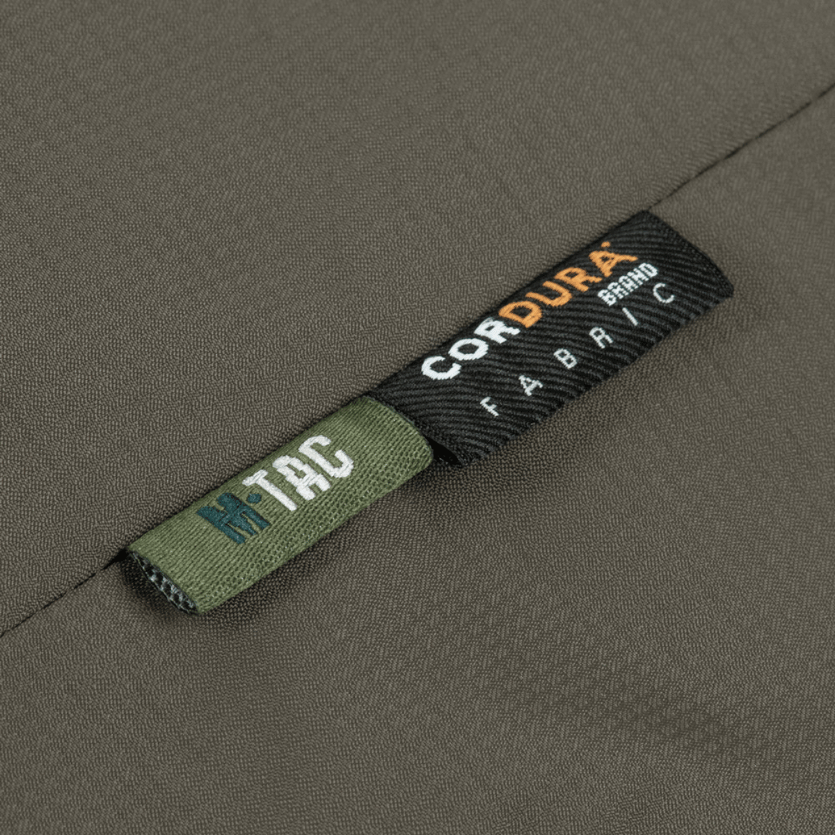 Etikette af M-Tac Alpha Gen.III Pro Vinterjakke med Cordura-stof, der viser holdbarhed og kvalitet, ideel til ekstreme forhold.