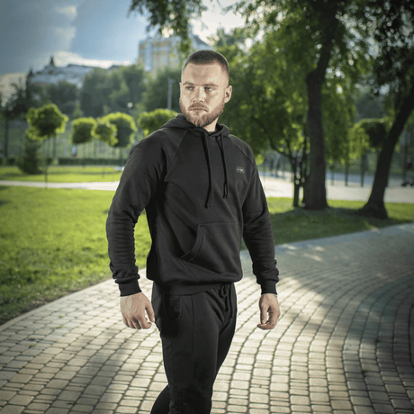 Mand iført M-Tac Hættetrøje Cotton Raglan i en park, fremhæver komfort og stil for både hverdagsbrug og aktiv livsstil.