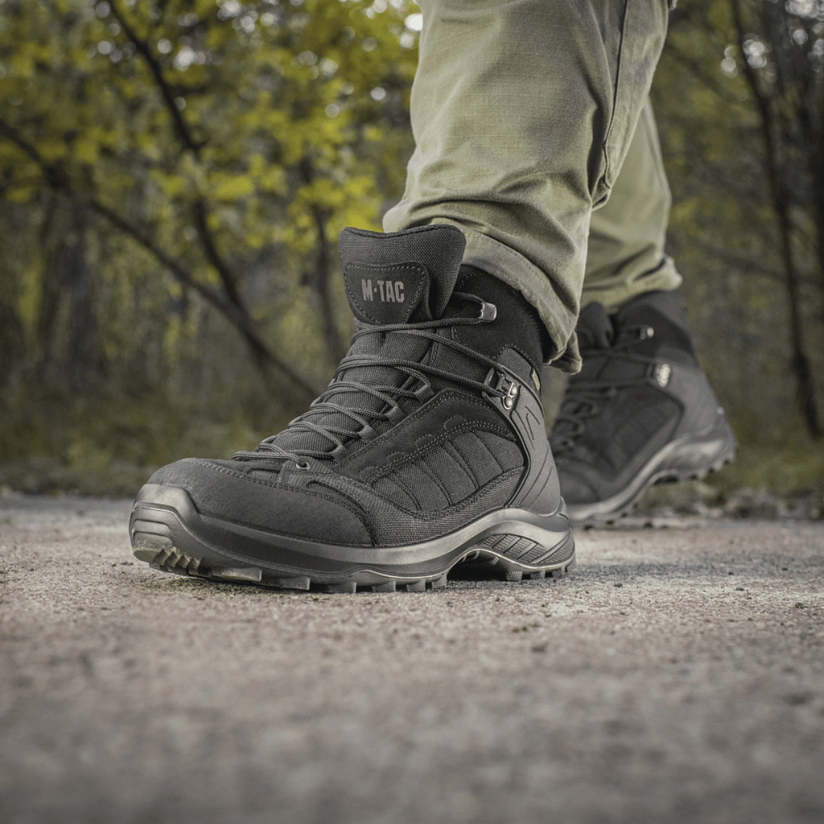 M-Tac Taktiske Sæsonstøvler i naturligt terræn, ideelle til outdoor-aktiviteter og taktiske opgaver.