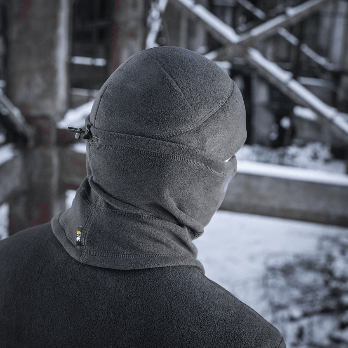 Alt Tag: M-Tac Anatomisk Tube Scarf med Snor Polartec i grå, beskytter mod elementer i en snefyldt, urban baggrund.