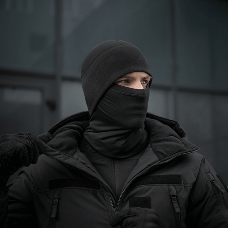 Person iført M-Tac Tube Scarf Polartec Power Grid, sort halsrør som maske i vintermiljø.