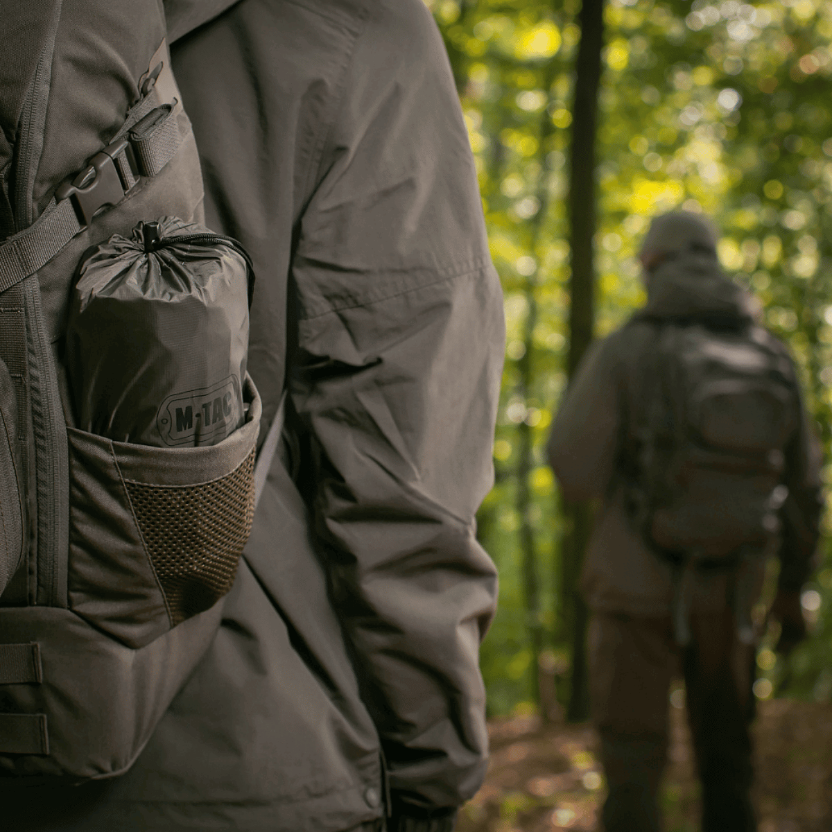 Vandrer bærer M-Tac Oppustelig Liggeunderlag 195x60 i skoven, praktisk pakket for camping og udendørseventyr.