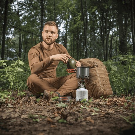 Man i skogen använder M-Tac Individuellt kokset för brännare vid camping, sitter vid brännare med ryggsäck.