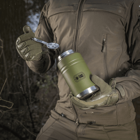 M-Tac termosflaska 750 ml med hopfällbar sked används utomhus, visar modern design och praktisk hopfällbar sked, perfekt för camping och vandring.
