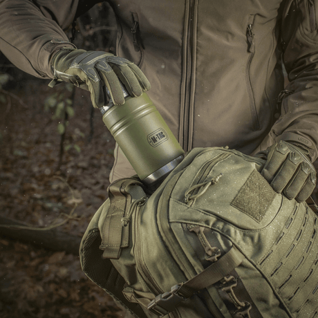M-Tac termosflaska 750 ml med hopfällbar sked för camping i skogsmiljö, robust design, bra för varma drycker, idealisk för utomhusbruk och äventyr.