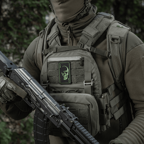 Person med M-Tac Patch Face of War (Broderi) på väst, broderat kranium, inspirerad av Vietnamkort, fäst med Velcro, taktisk utrustning.