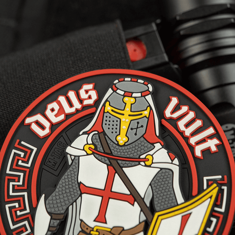 M-Tac Deus Vult 3D PVC-patch i 3D-design med riddarmotiv och texten 'Deus Vult', fästs med Velcro på taktisk utrustning. Diameter: 80 mm.