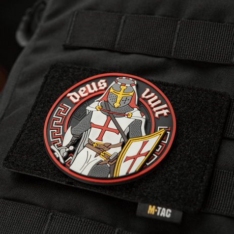 M-Tac Deus Vult 3D PVC-patch på en svart väska, visar en riddare med texten 'Deus Vult', fäst med Velcro. Idealisk för utomhusbruk.