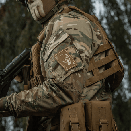 M-Tac Patch Face of War (Broderi) på en kamouflagejacka med ett oräddigt kraniemotiv inspirerat av Vietnamkrigets dödskort.