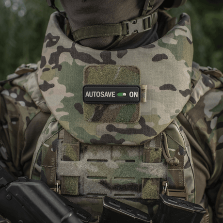 M-Tac Patch Autosave PVC i camo, monterad på militärväst för fokus och engagemang, med velcro-baksida för enkel fästning.