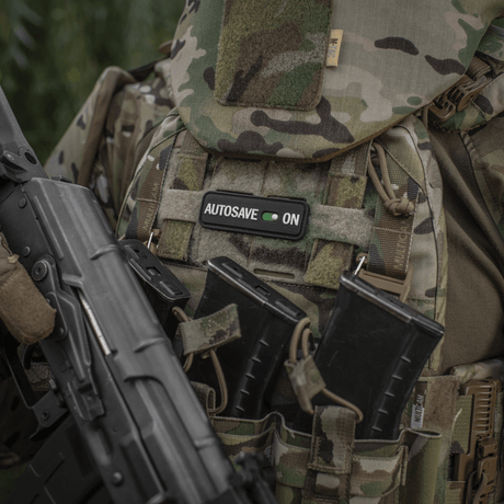 M-Tac Patch Autosave PVC på en camouflagetröja med magasinfickor, visar detaljerad 3D-design och färgklarhet, lämplig för taktisk användning.