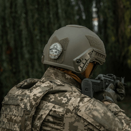 Soldat med taktisk hjälm och M-Tac Patch Emoji #4 i skogen, PVC med 3D-effekt och Velcro, morale patch, 6.5 x 6.5 cm, hållbar och rolig.