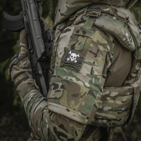 Soldat i uniform med M-Tac Patch Jolly Roger PVC på armen, fullfärgad 3D morale-patch med Velcro, symboliserar äventyrslust och beslutsamhet.