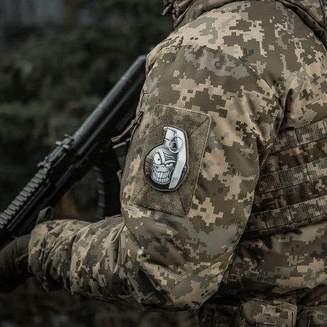 Militärentusiast i uniform med en M-Tac Patch M67 granat 3D PVC på ärmen, visar amerikansk M67-granat med emoji och text "Born to Kill".