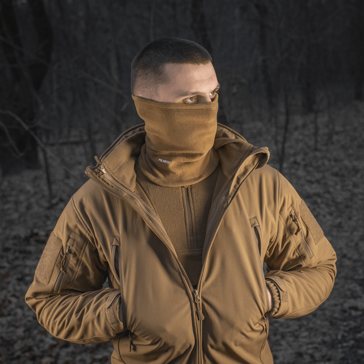 Mand iført M-Tac Tube Scarf Polartec som ansigtsmaske udendørs i skovomgivelser, ideel til kolde årstider og udendørsaktiviteter, Polartec fleece