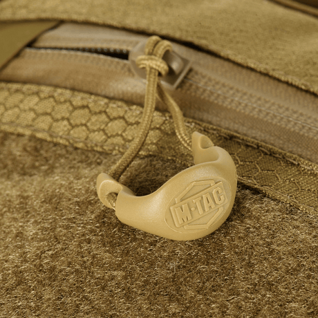 Detalj av M-Tac Sling pistolväska Elite Hex med Velcro, visar blixtlås och handtag med logotyp, i slitstarkt Cordura-material.