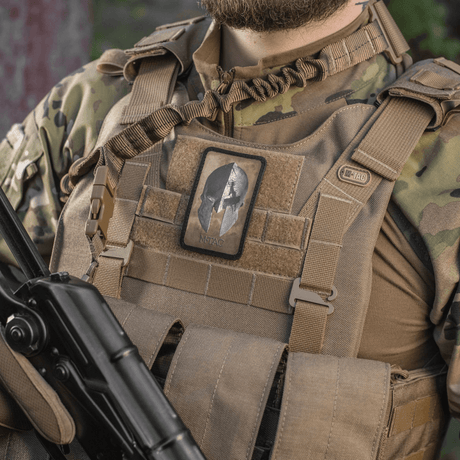 M-Tac Spartan Hjelm Patch fastsatt på taktisk väst, symboliserar mod och styrka, vintagedesign i slitstark Cordura 500D.