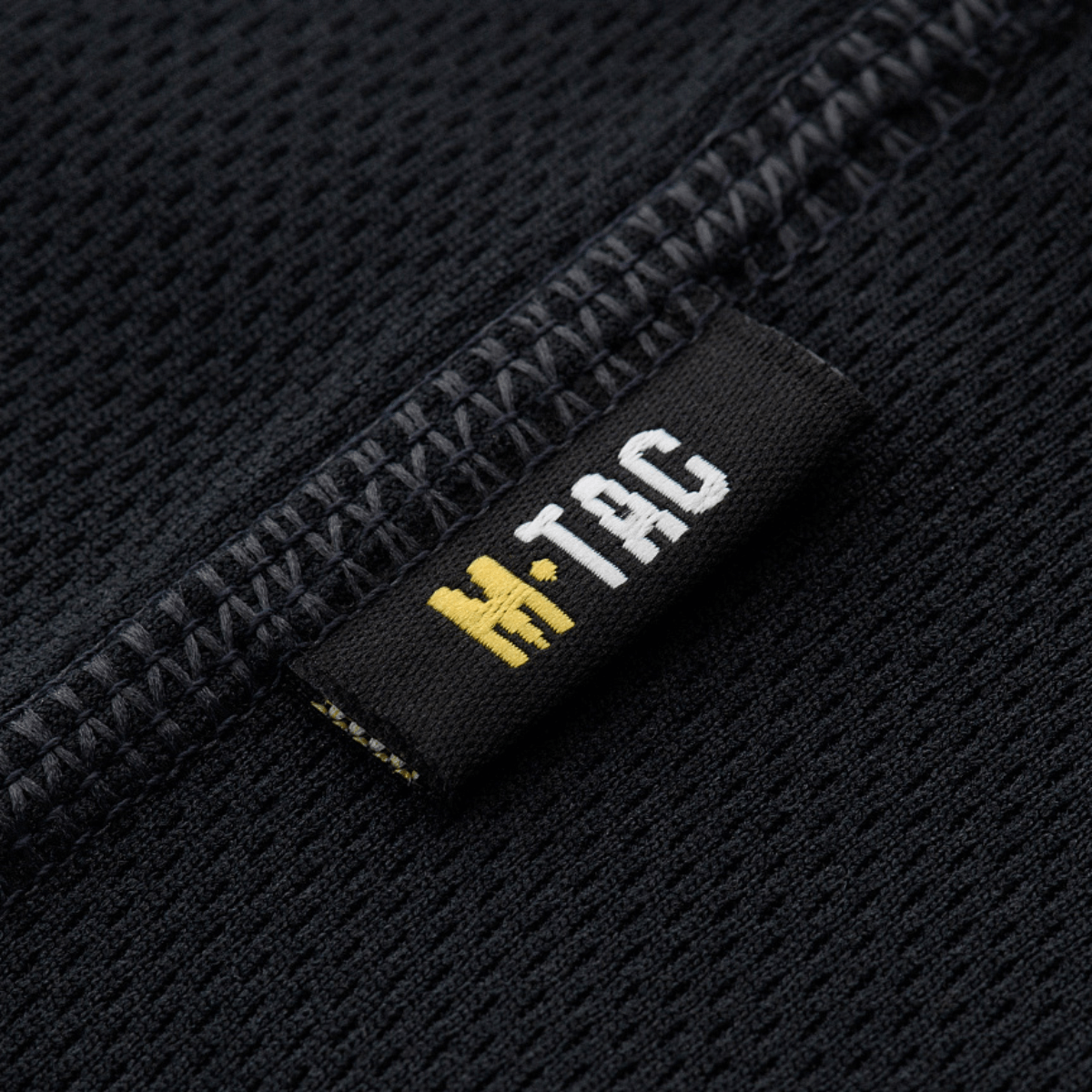 M-Tac Sweat-Wicking T-Shirt Athletic med svedtransporterende stof og anatomisk pasform, zoom på tøjets søm og logo label.